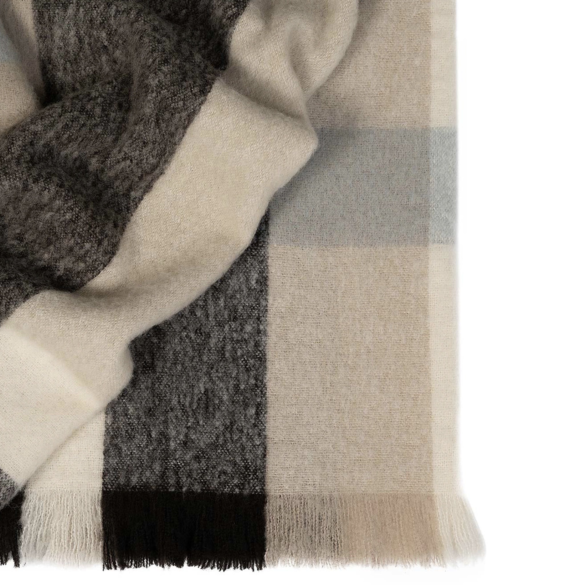 Close-up of a checkered blanket with gray, beige, and black colors on a white background.