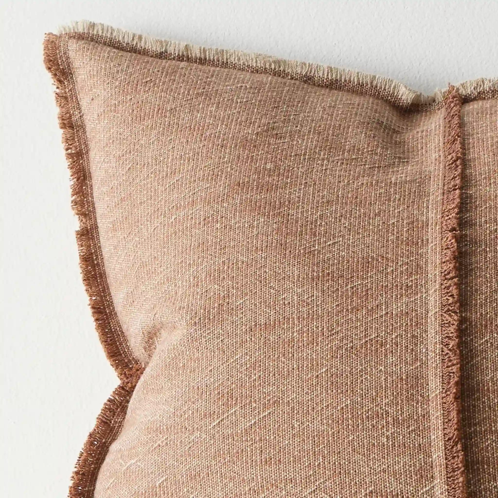 Close-up of a textured brown cushion with frayed edges on a light background