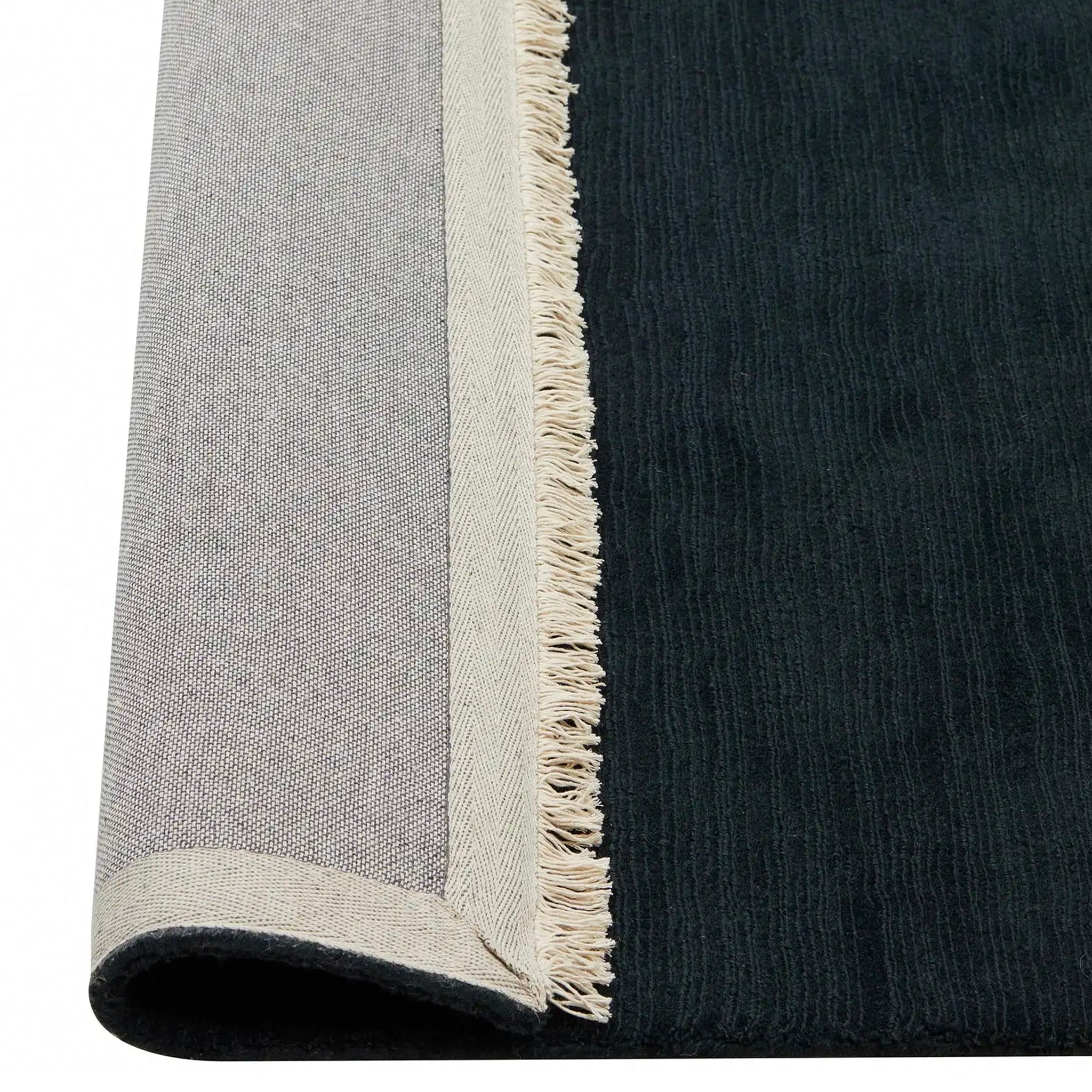 Close-up of a black and gray rug with fringed edge