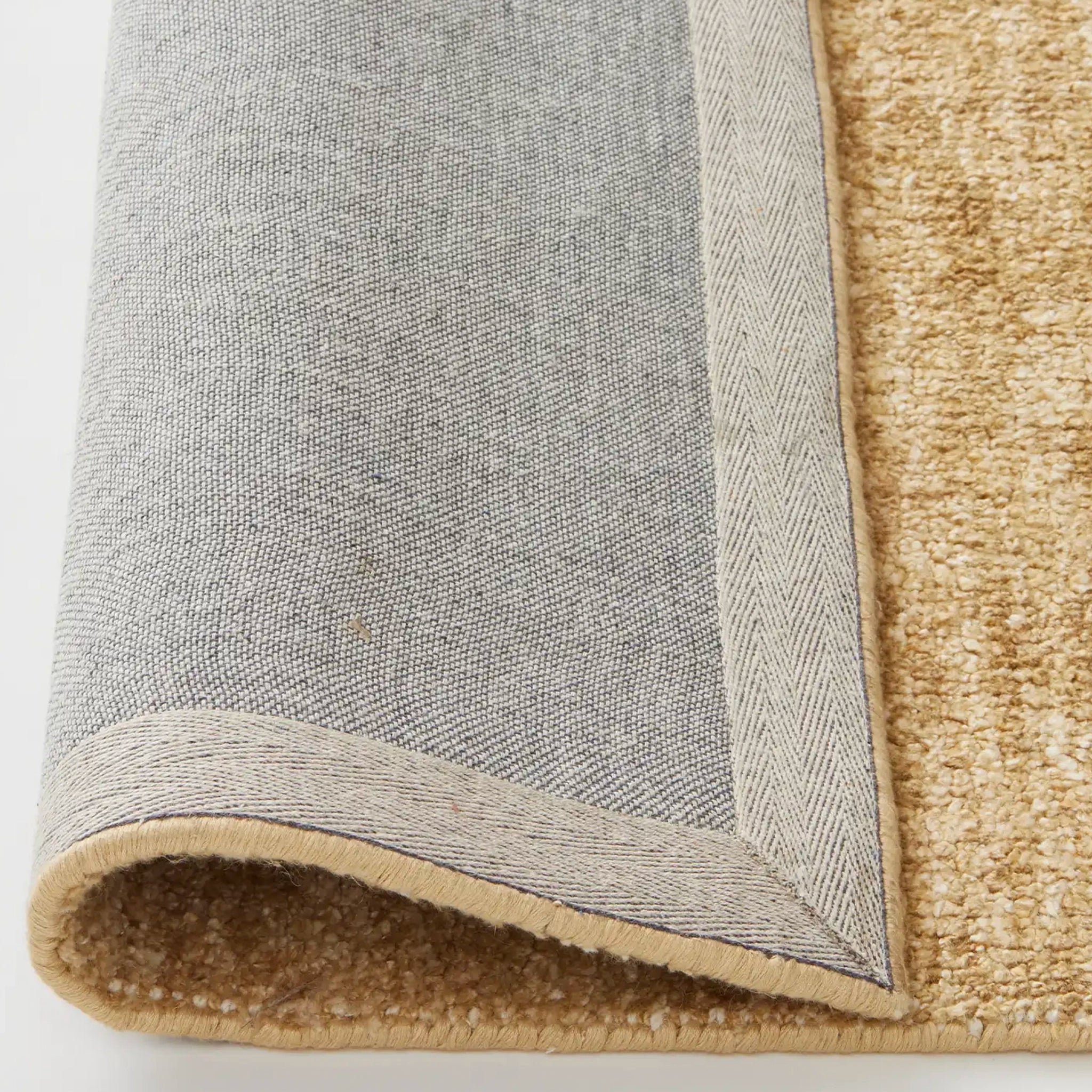 Close-up of a gray and beige textured rug corner.