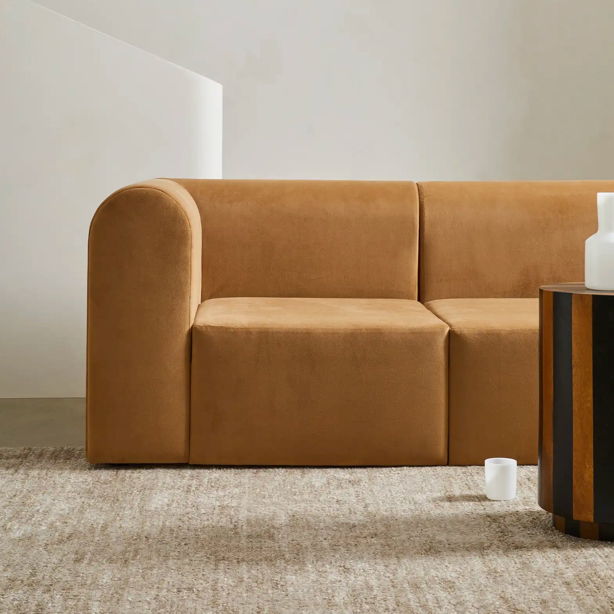 Brown sofa in a minimalistic room with a side table and decorative item.