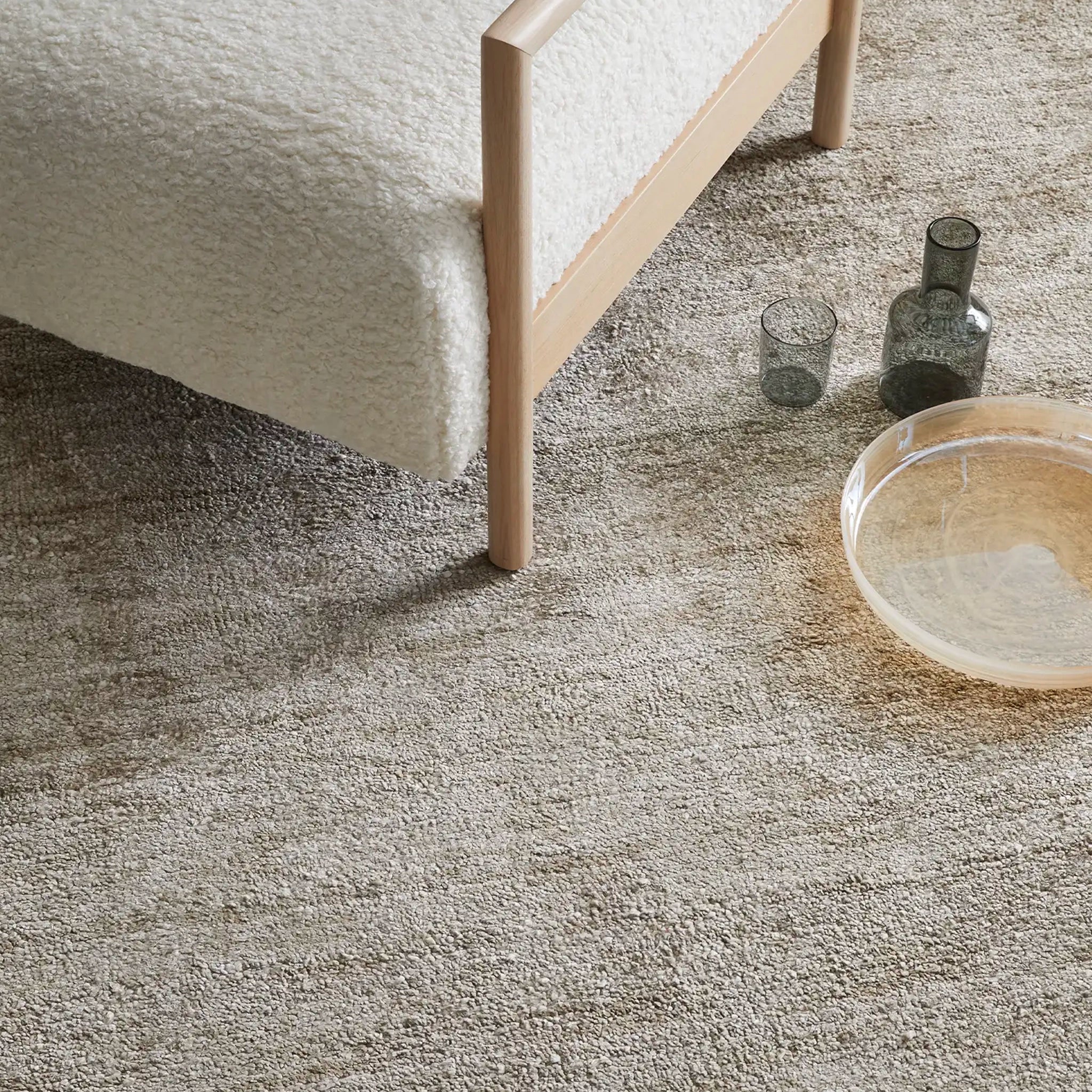Textured gray carpet with a wooden bed frame and decorative items.