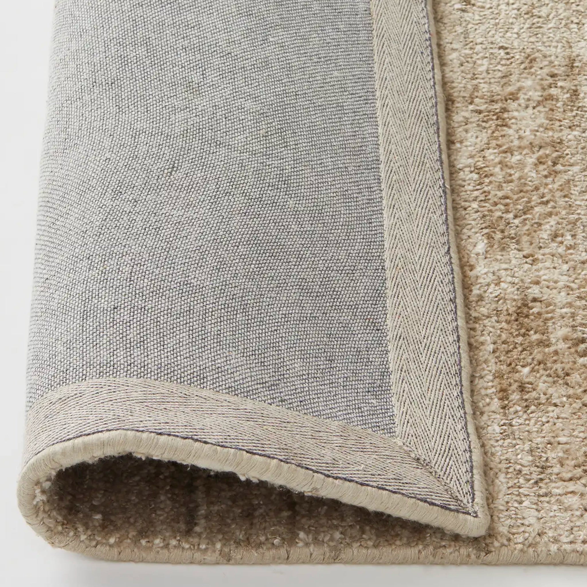 Close-up of a gray and beige rug corner on a white background