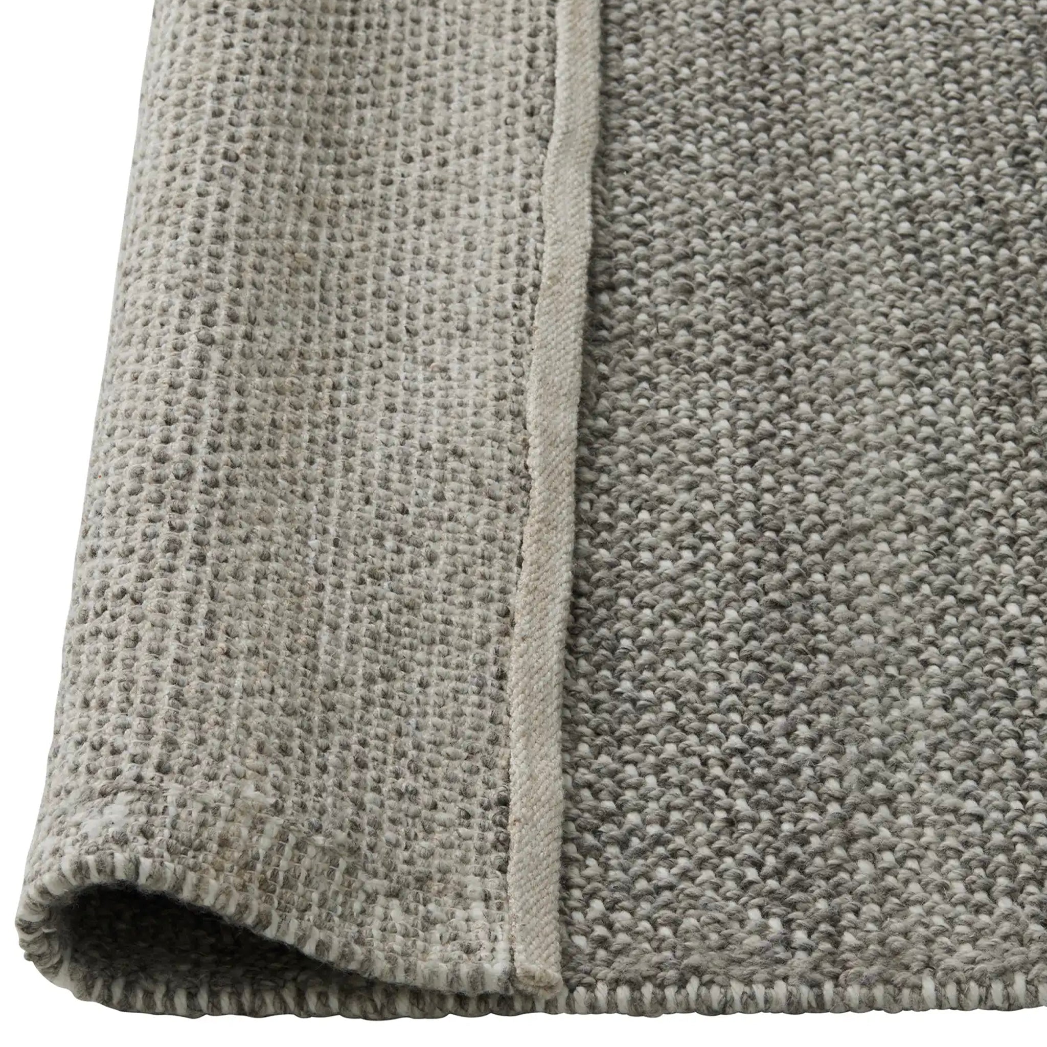 Close-up of a textured gray rug with a visible seam on a white background