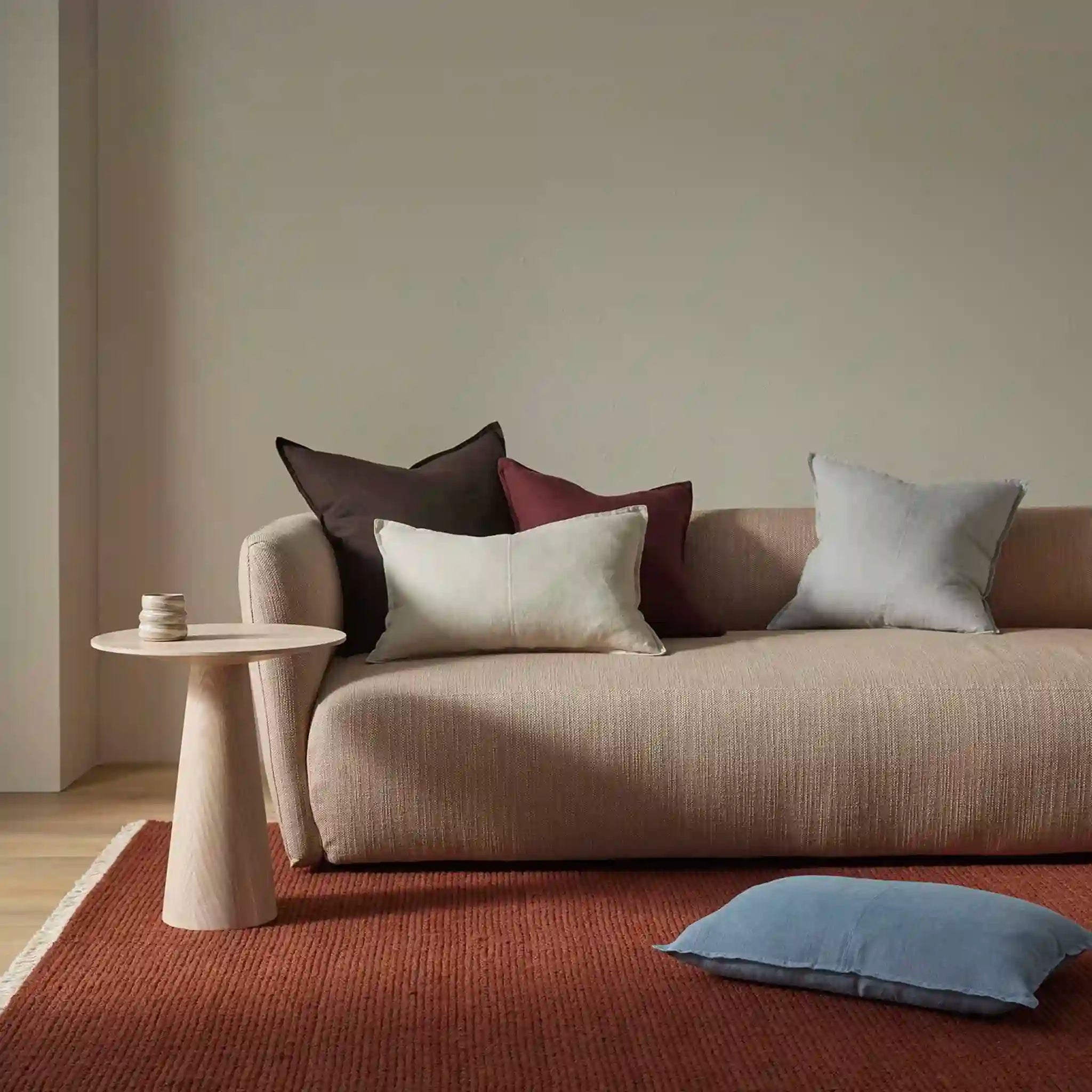 Beige sofa with colorful cushions in a minimalistic living room.