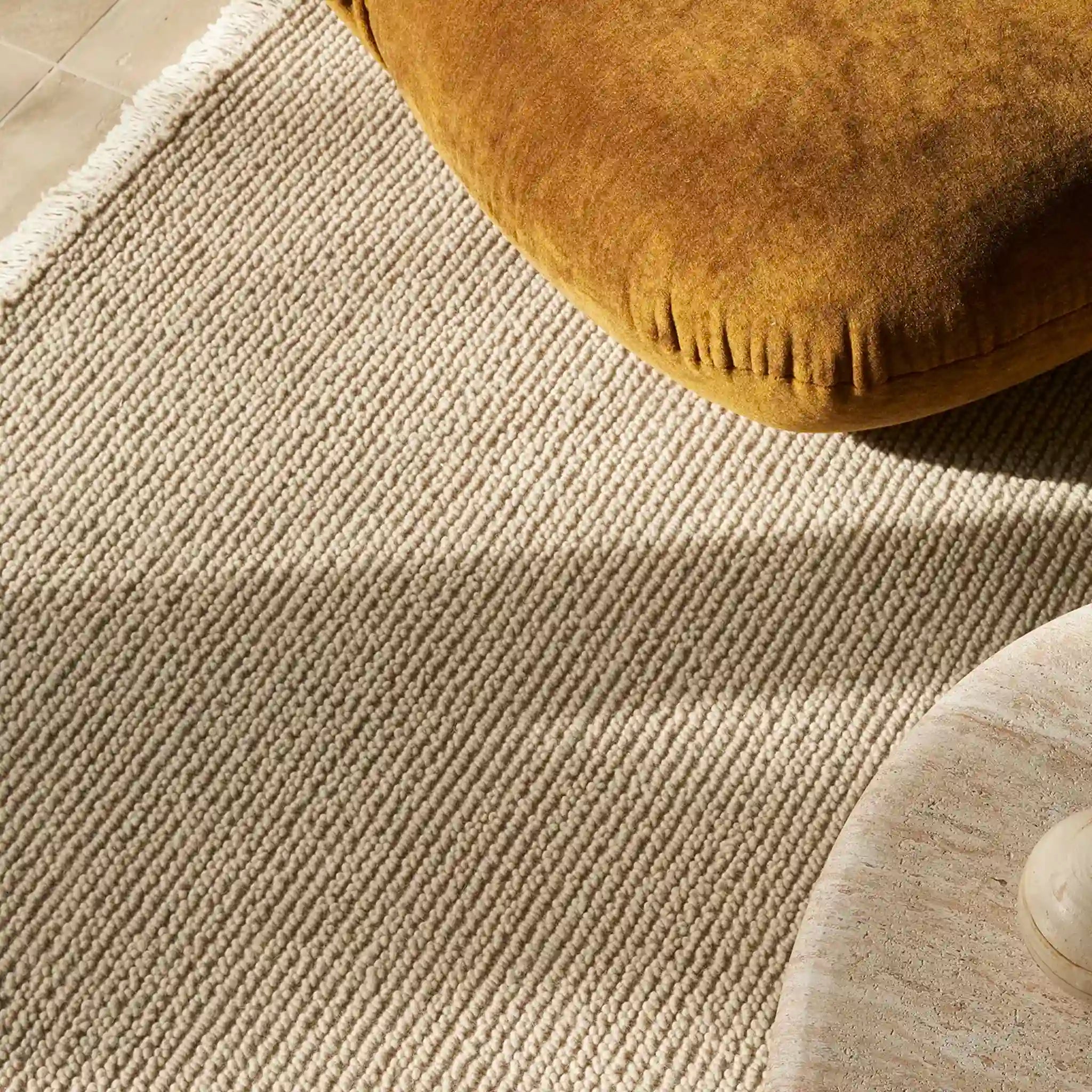 Close-up of a textured beige rug with a brown cushion on top