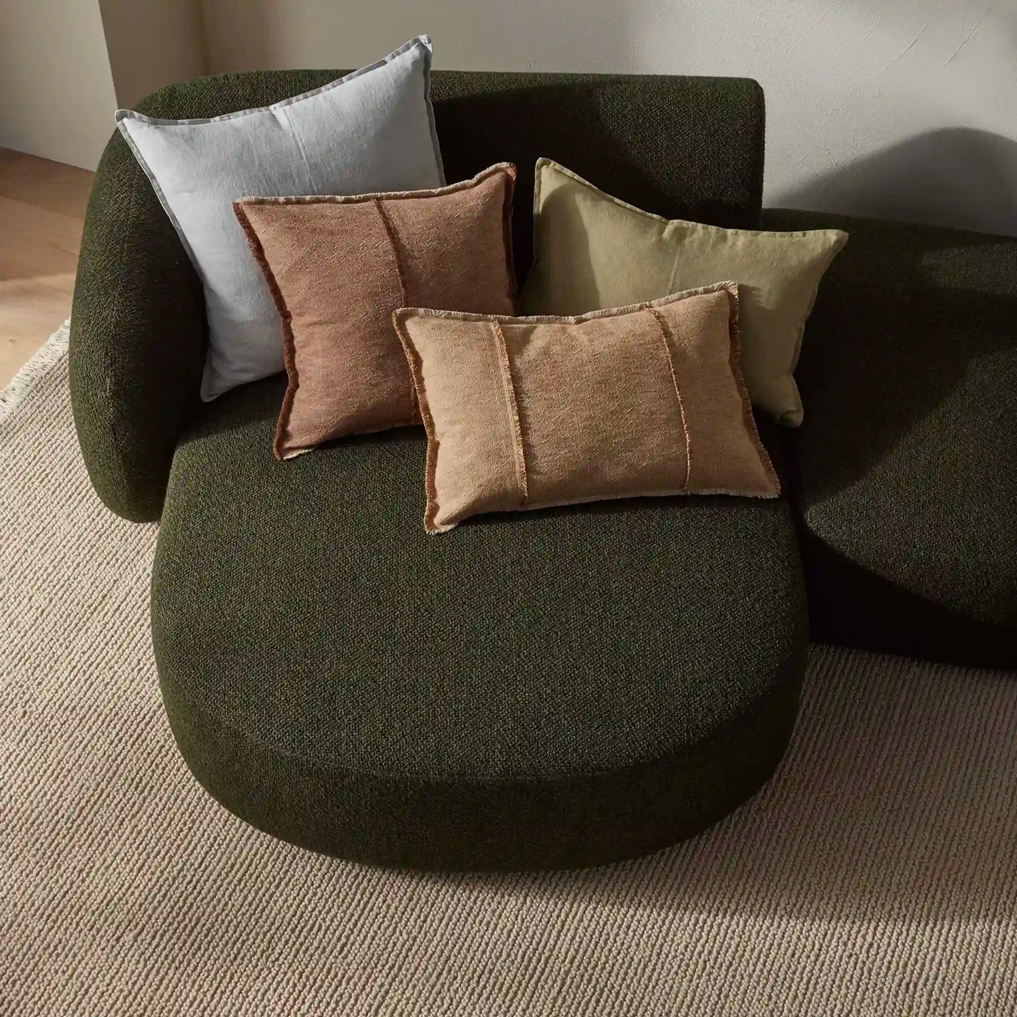 Green armchair with colorful cushions on a neutral background