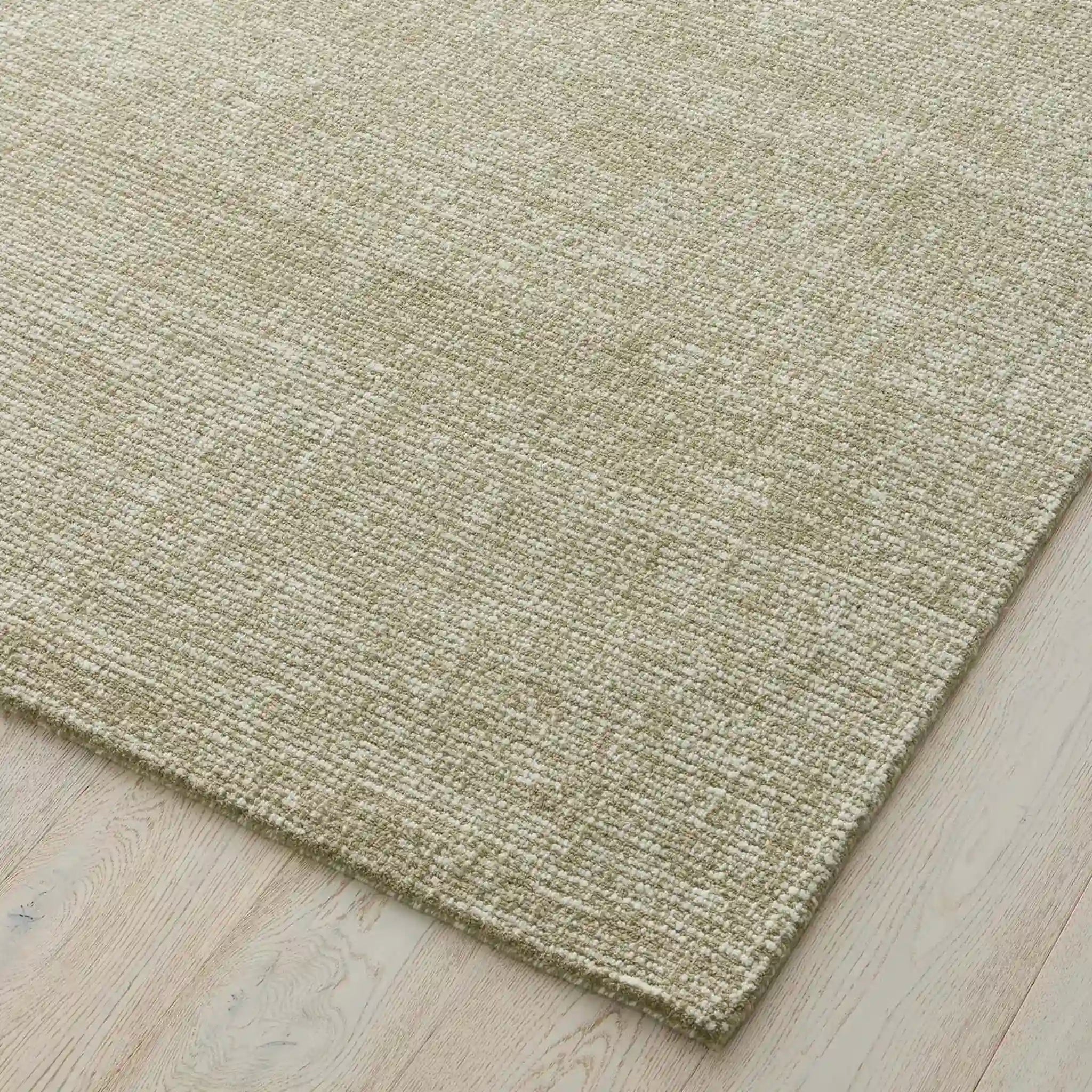 Close-up of a textured green rug on a wooden floor