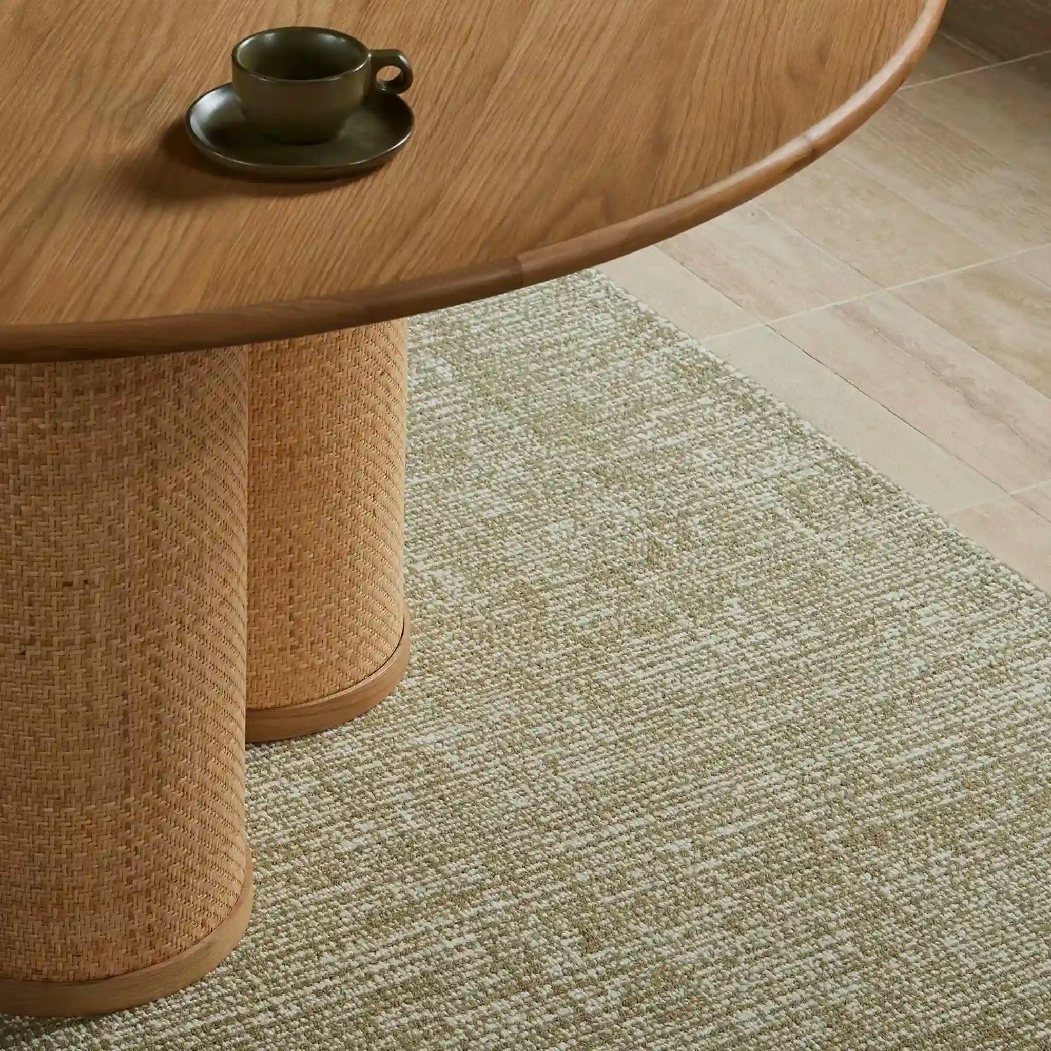Round wooden table with a woven base on a textured rug