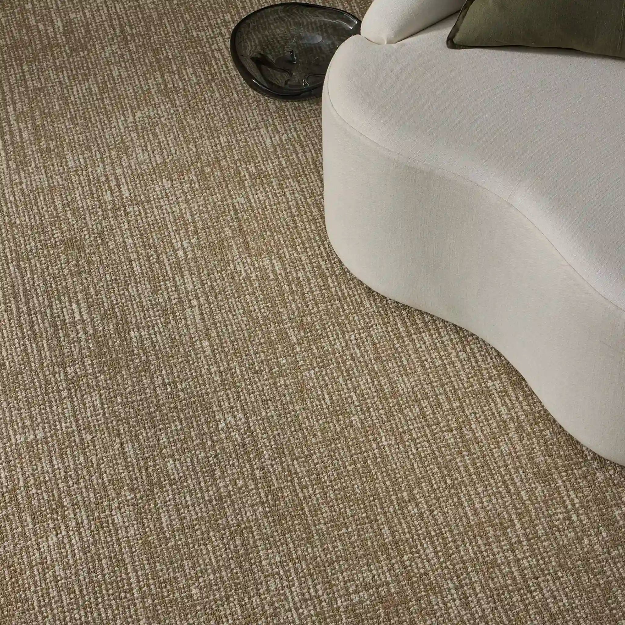 Textured beige carpet with a white chair and green pillow in the corner.