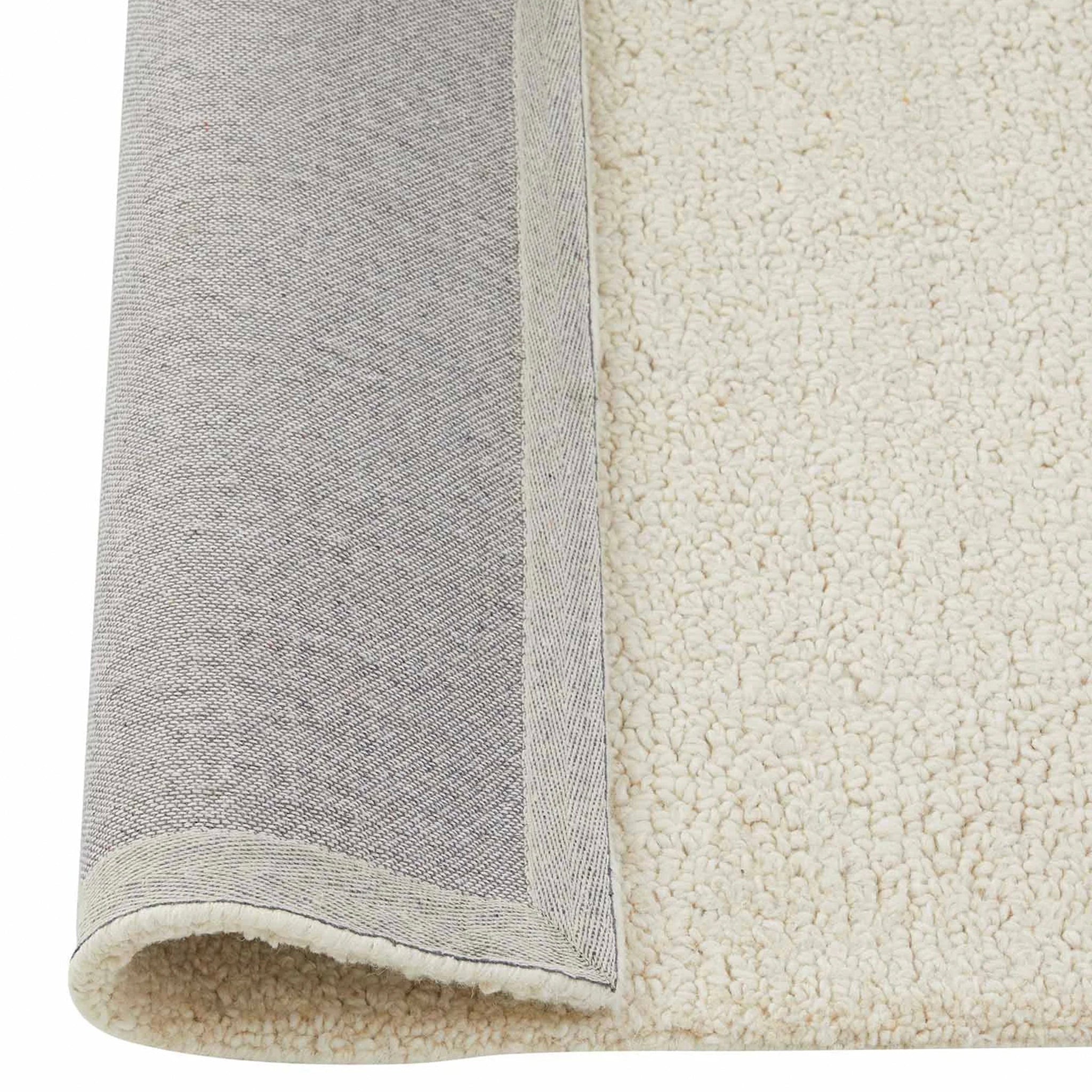 Close-up of a textured rug with a gray border and beige surface.