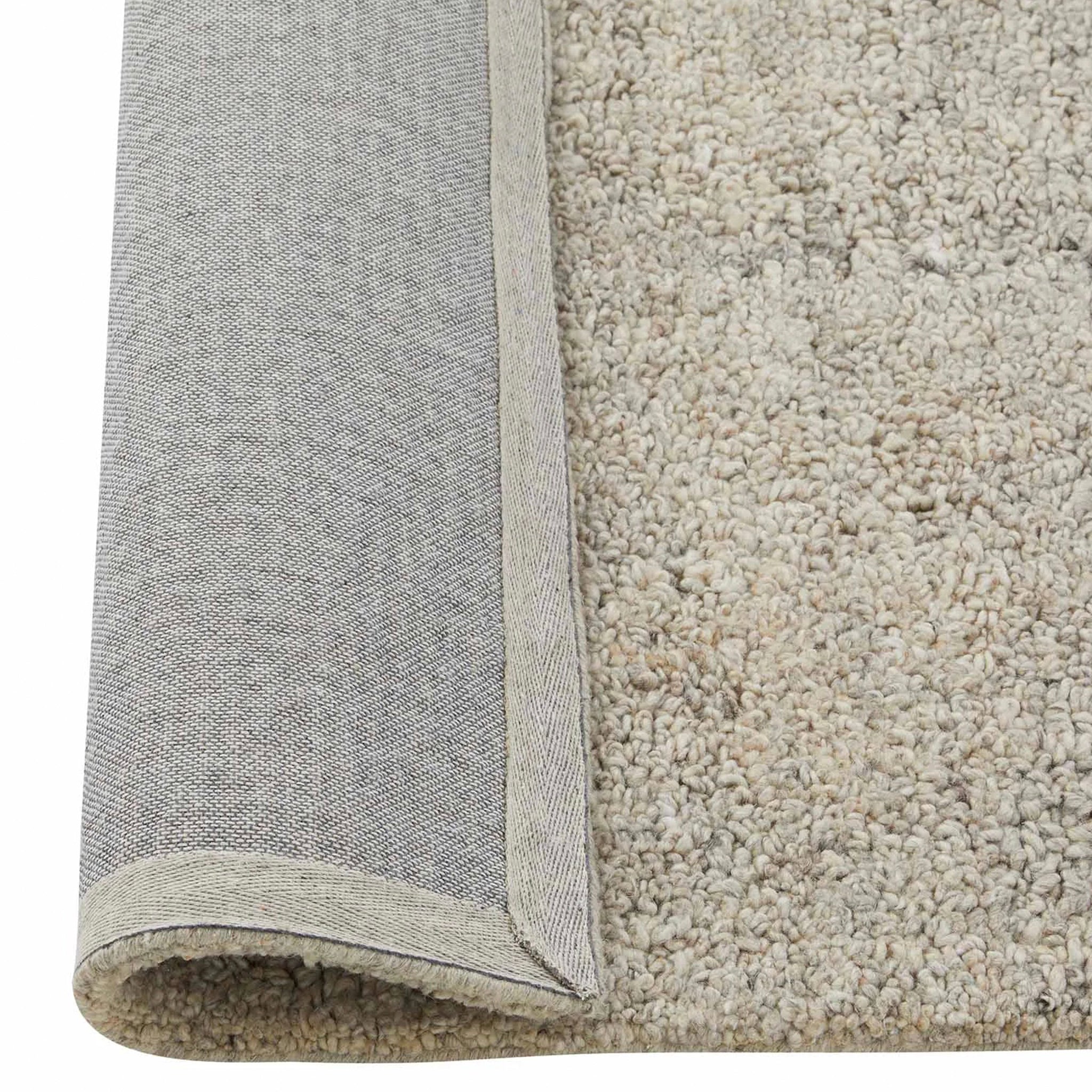 Close-up of a beige and gray textured rug corner