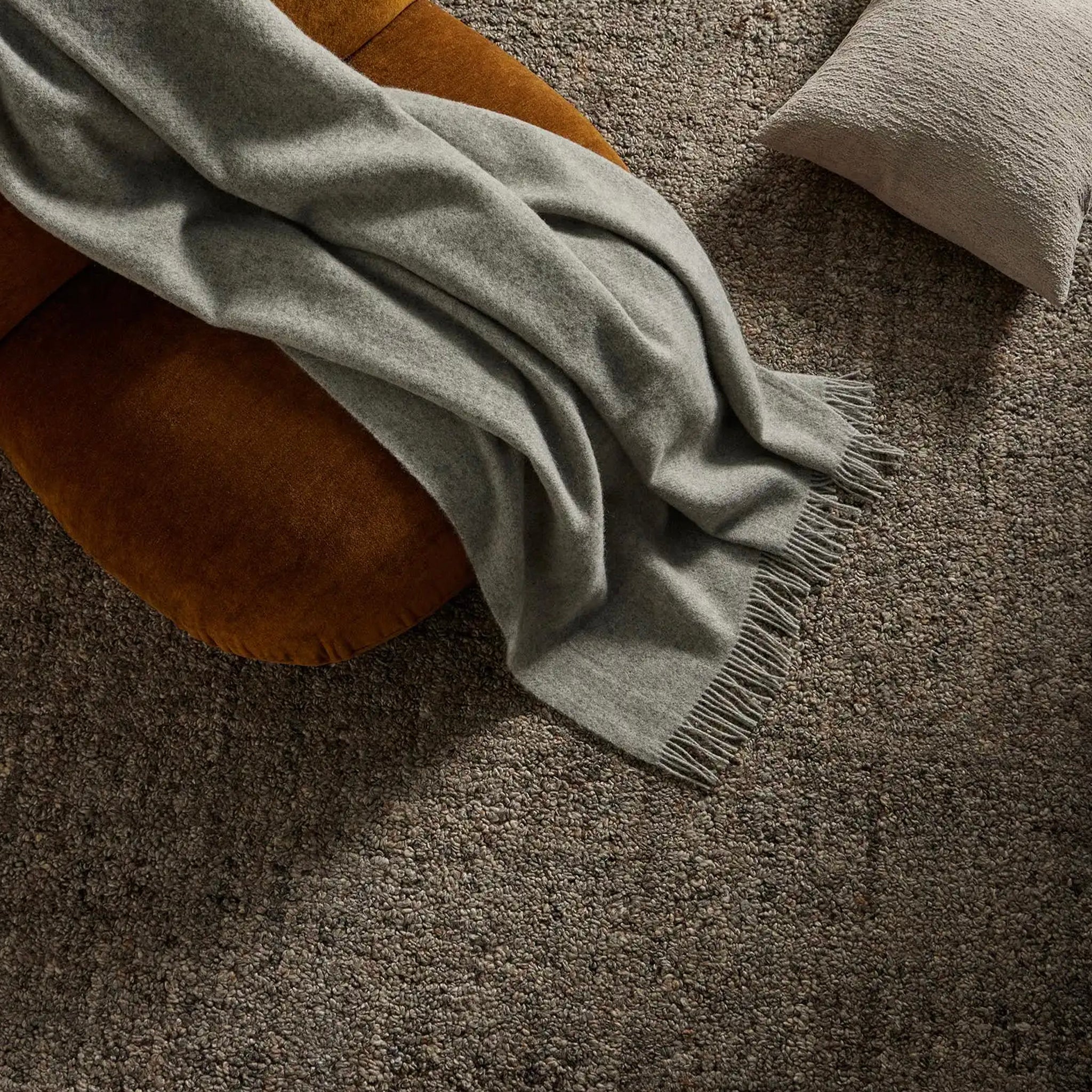 Green blanket draped over a brown cushion on a textured surface