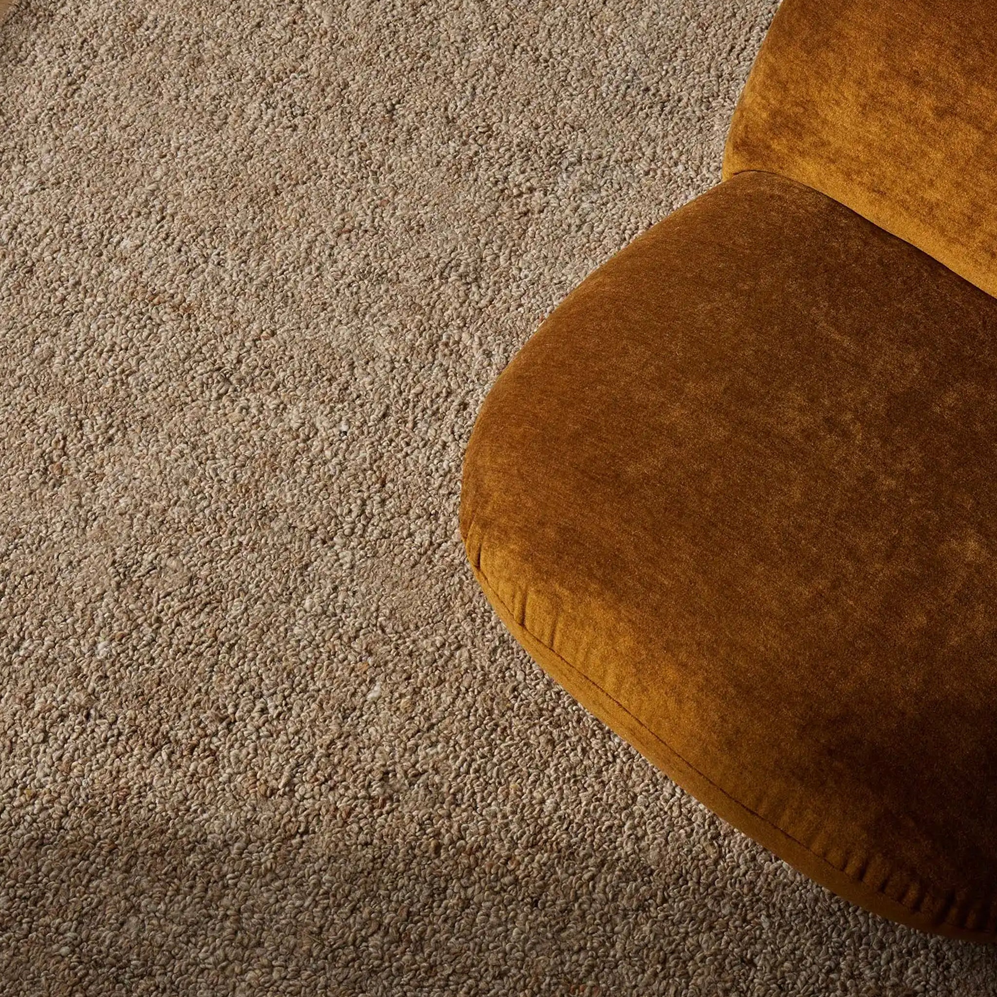 Brown cushion on a textured beige carpet