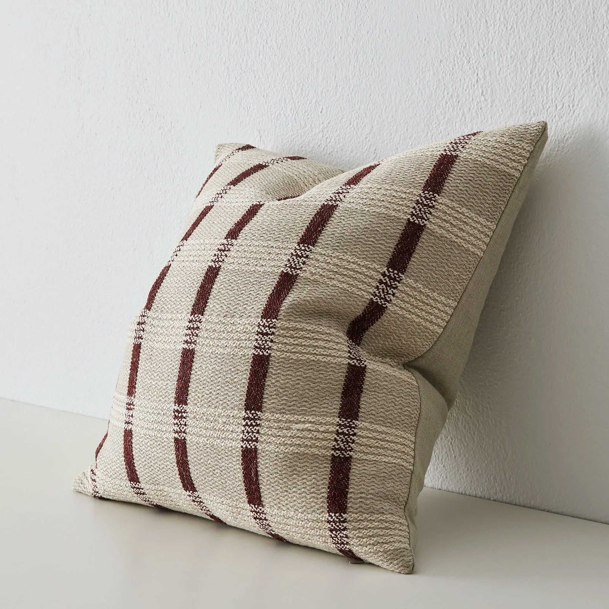 Plaid patterned pillow on a light surface with a white background