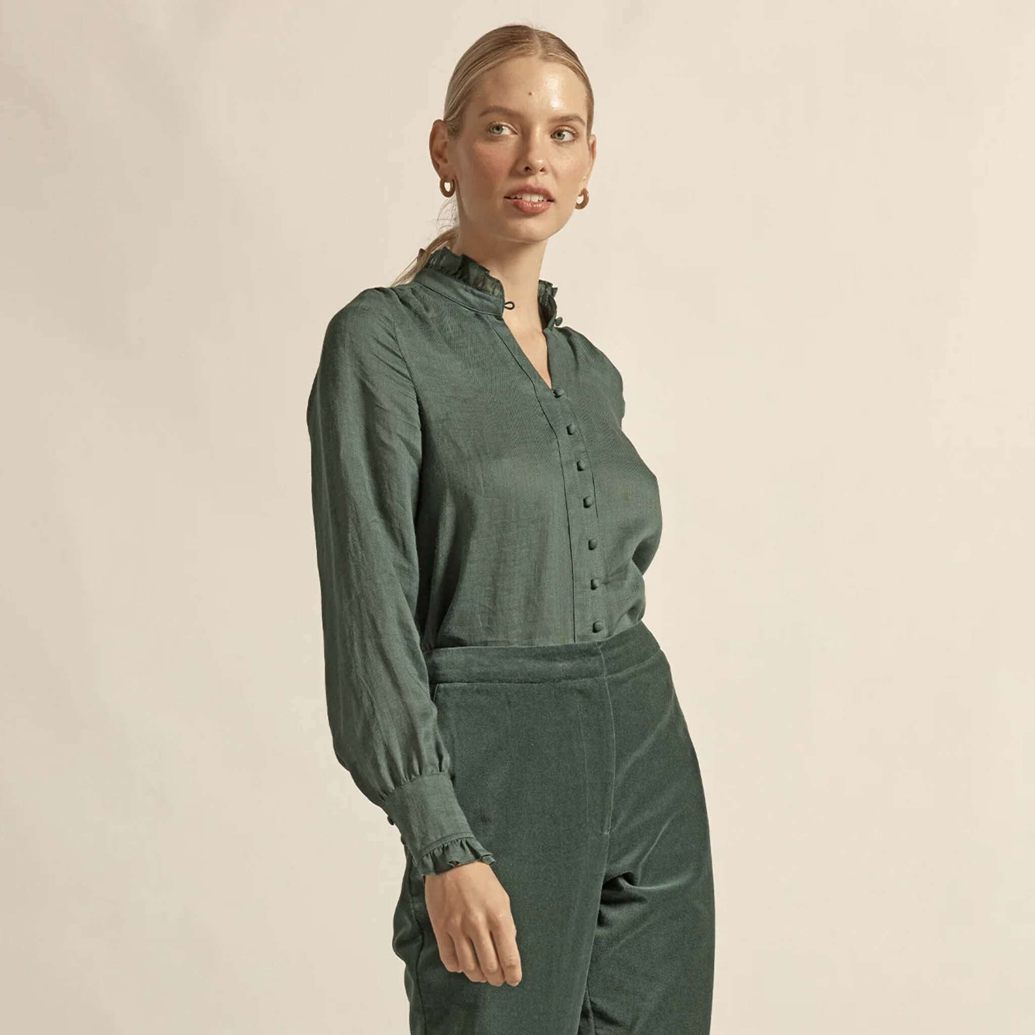 Alt Tag: Zoe Kratzmann Stir Top - Grove green ramie blouse with ruffle neckline and v-neck, long sleeves, front button detail on model