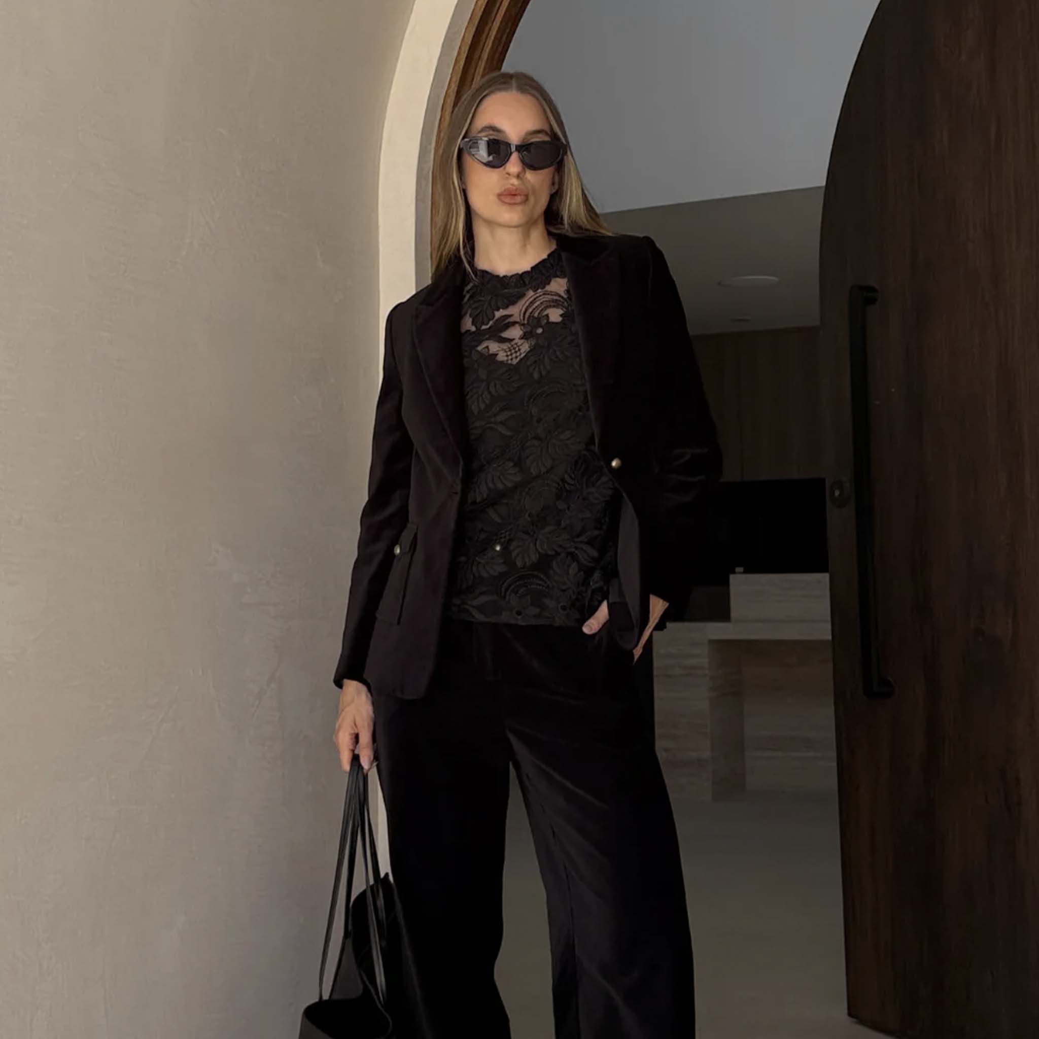Alt Tag: Zoe Kratzmann Glint Top - Black lace top styled with blazer and pants, long sleeves with frill neckline, elevated evening look