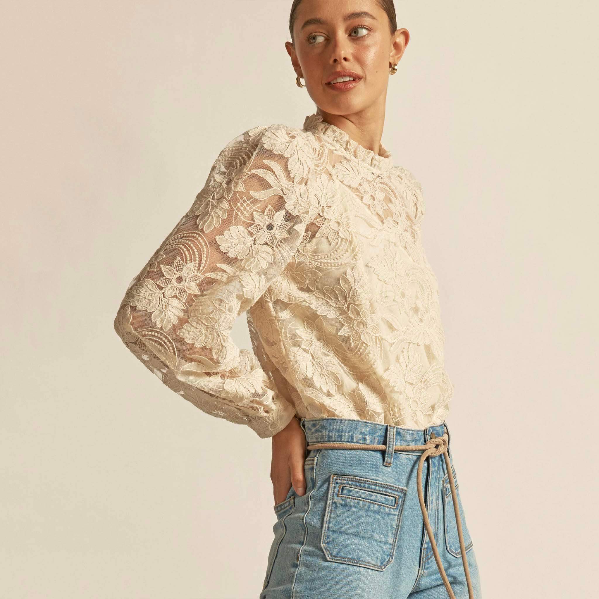Alt Tag: Zoe Kratzmann Glint Top - Ecru intricate lace long sleeve top with frill neckline, styled with high-waisted jeans