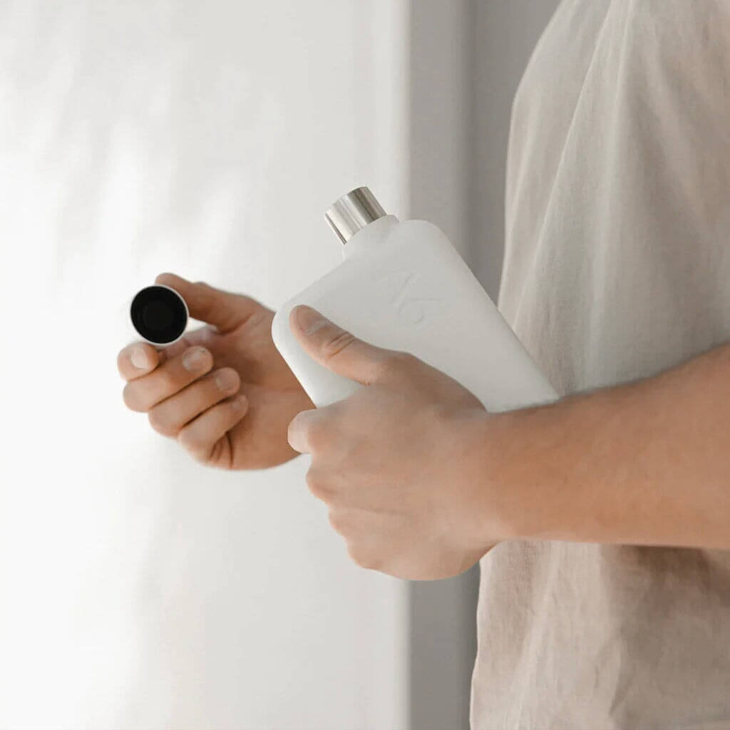Memobottle A5 Stainless Steel - White flat water bottle in hand with cap removed, space-saving design for all-day hydration