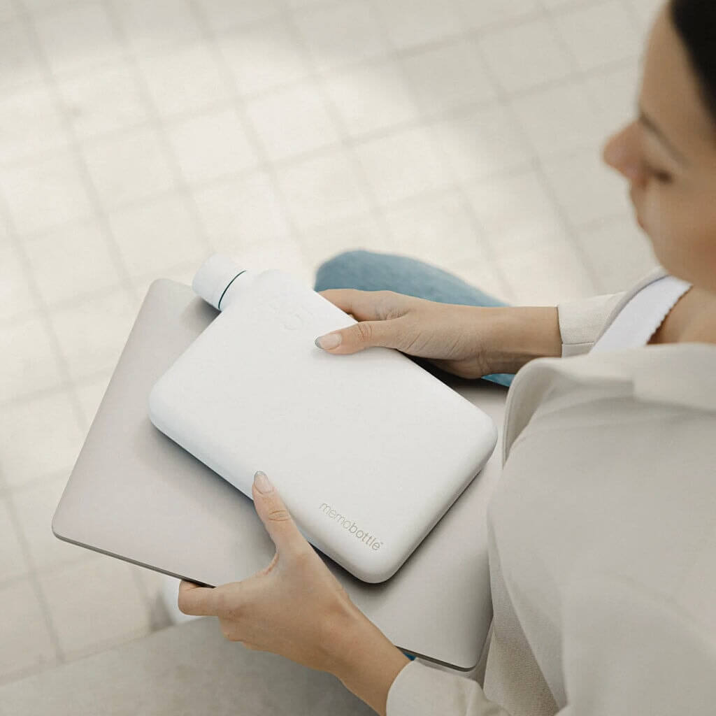 Alt Tag: Memobottle A5 Stainless Steel - White flat water bottle held on laptop for space-saving all-day hydration